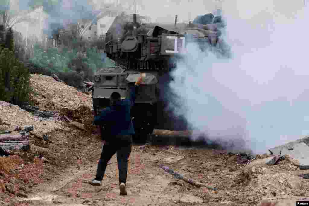 A man throws a stone at an Israeli tank during an Israeli operation in Jenin, in the Israeli-occupied West Bank.