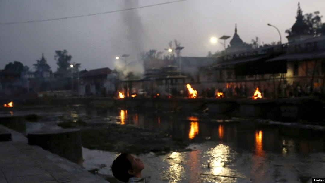 Seorang anak duduk di anak tangga kuil Pashupathinath (1/5) sementara warga berdoa, enam hari setelah gempa dahsyat di Kathmandu, Nepal. (REUTERS/Olivia Harris)
