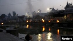 Seorang anak duduk di anak tangga kuil Pashupathinath (1/5) sementara warga berdoa, enam hari setelah gempa dahsyat di Kathmandu, Nepal. (REUTERS/Olivia Harris)