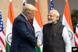 FILE - Former U.S. President Donald Trump, left, and Indian Prime Minister Narendra Modi shake hands before meeting in New Delhi, India, Feb. 25, 2020. Some Republican activists are betting Trump's close ties to Modi will translate into votes for Trump in November.