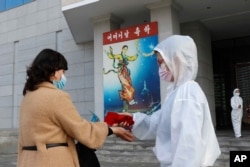 A woman has her temperature checked outside a perfromance for Mother's Day in Pyongyang, North Korea, Nov., 16, 2020.