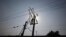 A technician is silhouetted as he works on power lines supplying electricity in the outskirts of Lahore, Pakistan, Jan. 31, 2012.