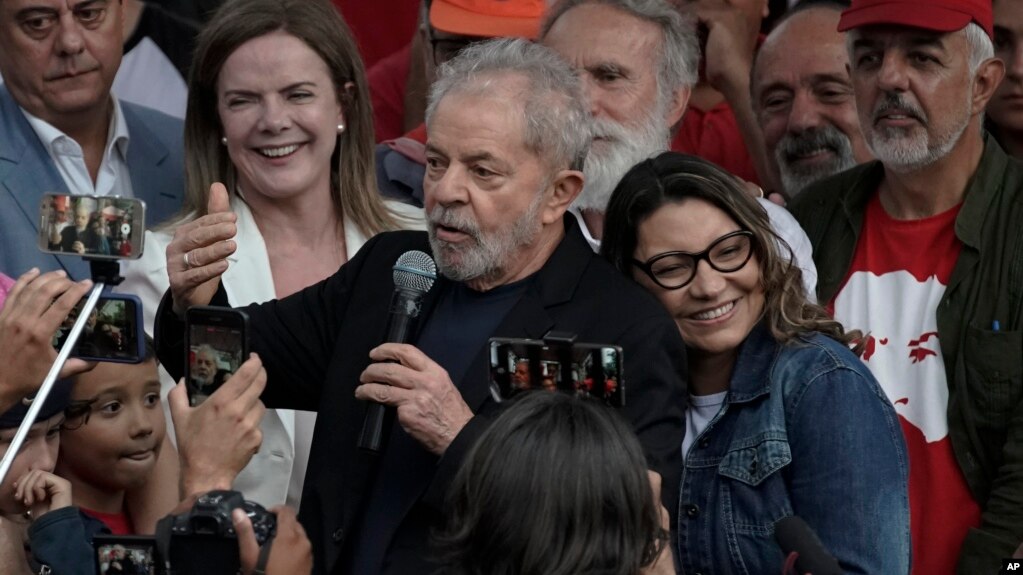 El expresidente de Brasil Luiz Inacio Lula da Silva habla a simpatizantes junto a su novia Rosangela da Silva eans on his back after he was released from Federal Police headquarters where he was imprisoned on corruption charges in Curitiba, Brazil,…