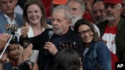 El expresidente de Brasil Luiz Inacio Lula da Silva habla a simpatizantes junto a su novia Rosangela da Silva eans on his back after he was released from Federal Police headquarters where he was imprisoned on corruption charges in Curitiba, Brazil,…