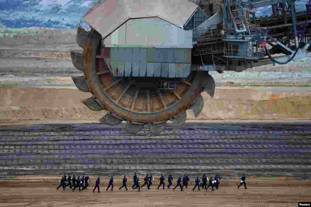 Riot police run past an excavator, during a demonstration against open-cast brown coal mining of Garzweiler, northwest of Cologne, Germany,.