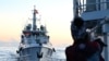 FILE - A Philippines coast guard member looks at the Chinese Coast Guard vessel as they come close during a mission to deliver provisions at Second Thomas Shoal in the South China Sea on November 10, 2023.