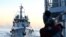 FILE - A Philippines coast guard member looks at the Chinese Coast Guard vessel as they come close during a mission to deliver provisions at Second Thomas Shoal in the South China Sea on November 10, 2023.