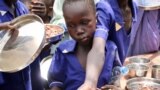 Children push their plates out to receive a portion of cooked grains during a lunchtime feeding program initiative by UNICEF and WFP with the aim of providing daily meals to 75,000 children in Aweil, N. Bahr el Ghazal state, S. Sudan, March 26, 2019.