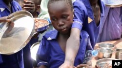 Children push their plates out to receive a portion of cooked grains during a lunchtime feeding program initiative by UNICEF and WFP with the aim of providing daily meals to 75,000 children in Aweil, N. Bahr el Ghazal state, S. Sudan, March 26, 2019.