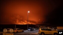 La carretera de ingreso a Grindavík está bloqueada mientras se ve la erupción de fondo. En la península de Reykjanes, Islandia, el lunes 18 de diciembre de 2023.