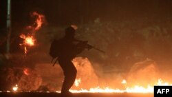 Un soldado israelí pasa frente a unas llantas quemadas en protesta en la Franja de Gaza.