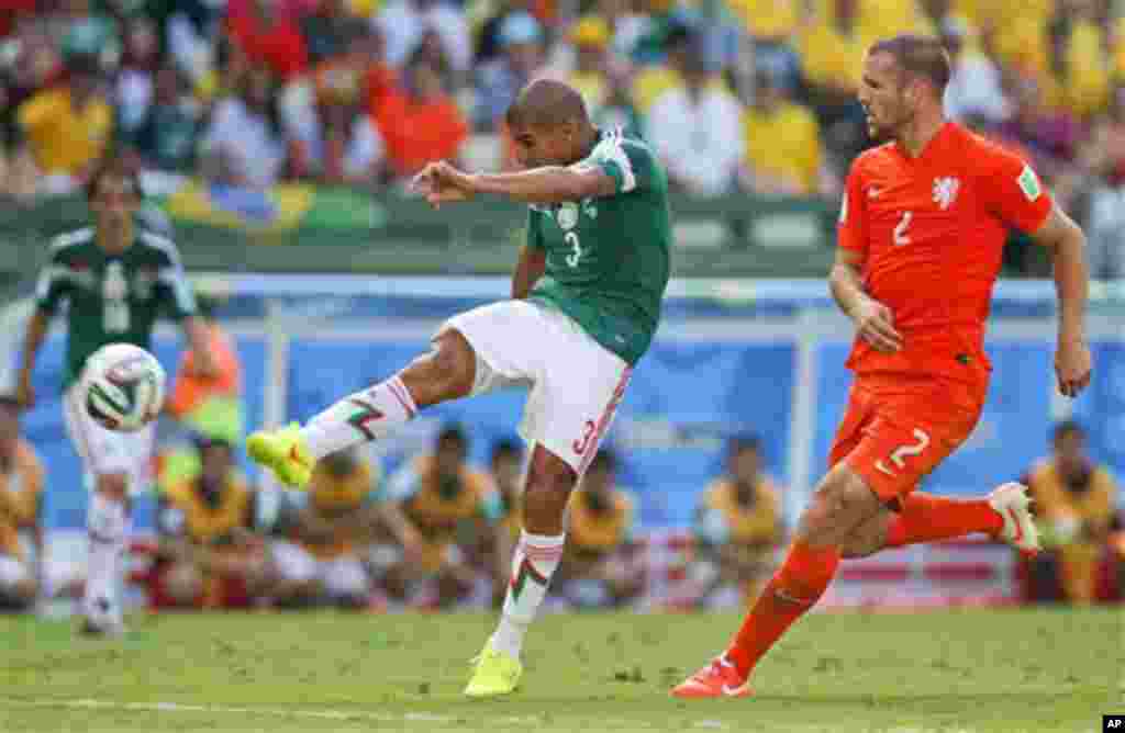 Netherlands' Ron Vlaar keeps an eye on Mexico's Carlos Salcido as he takes a shot on goal during the World Cup round of 16 soccer match between the Netherlands and Mexico at the Arena Castelao in Fortaleza, Brazil, Sunday, June 29, 2014. (AP Photo/Eduardo