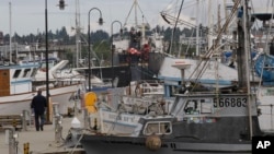 FILE - A man walks on a dockat Fishermen's Terminal in Seattle, Washington, July 2, 2010. 