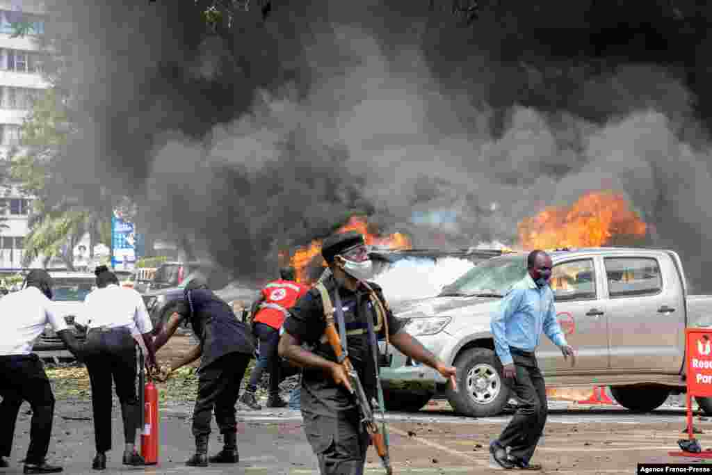 People extinguish a fire caused by a bomb explosion near the Parliament building in Kampala, Uganda. Two explosions hit the central business district of Kampala near the central police station and the entrance to Parliament, killing three civilians and injuring a number of people, police said.