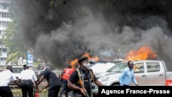 Warga berusaha memadamkan mobil yang terbakar pasca ledakan dekat gedung parlemen Uganda di Kampala, Selasa (16/11). 