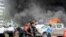 FILE - People extinguish vehicle fires caused by a bomb explosion near the parliament building in Kampala, Uganda, on Nov. 16, 2021.
