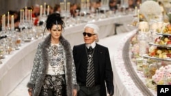 FILE - German fashion designer Karl Lagerfeld, with British model Stella Tennant, left, acknowledges applause at the end of the presentation of his Paris-Bombay collection for Chanel, in Paris, Dec. 6, 2011.