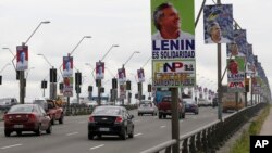 Automóviles cruzan un puente flanqueado por avisos de campaña promoviendo al candidato presidencial Guillermo Lasso del Partido CREO (izquierda) y del oponente Lenin Moreno, candidato del partido gubernamental Alianza País.