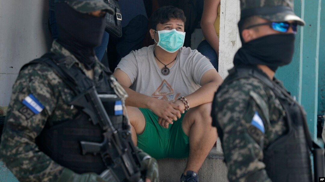 Un ciudadano pertrechado con una máscara sanitaria observa a dos miembros de las fuerzas de seguridad hondureñas, que hacen guardia en las calles de Tegucigalpa, el 17 de marzo de 2020.