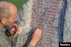 Local man Frank Lesjean repaints the names of fallen U.S. soldiers of the First World War’s 371st infantry regiment, an African American unit, onto a granite monument on a ridge surrounded by fields, near the eastern French village of Ardeuil-et-Montfauxelles.