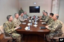 FILE - The U.S. chairman of the Joint Chiefs of Staff, Gen. Joseph Dunford, third left, and Turkey's Chief of Staff Gen. Hulusi Akar, third right, talk during a meeting in Incirlik Airbase in Turkey, Feb. 17, 2017.