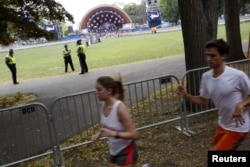 Runners pass by the Hatch Memorial Shell stage as officials prepare to celebrate Independence Day a day early in Boston, Massachusetts, July 3, 2014.