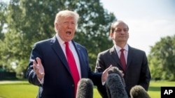 President Donald Trump, accompanied by Labor Secretary Alex Acosta, right, speaks to members of the media on the South Lawn of the White House in Washington, July 12, 2019.