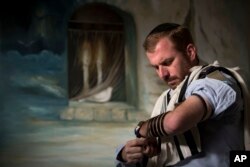 FILE— In this photo taken April 30, 2014, Jewish ultra-Orthodox military captain Moshe Prigan, 30, lays phylacteries for his morning prayer at home in the ultra-Orthodox Jewish town of Bnei Brak, near Tel Aviv, Israel.