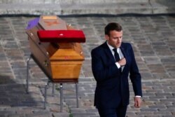 FILE - French President Emmanuel Macron leaves after paying his respects by the coffin of slain teacher Samuel Paty in the courtyard of the Sorbonne university during a national memorial event, Oct. 21, 2020, in Paris.
