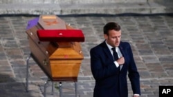 French President Emmanuel Macron leaves after paying his respects by the coffin of slain teacher Samuel Paty in the courtyard of the Sorbonne university during a national memorial event, Oct. 21, 2020, in Paris. 