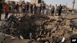 FILE - Civilians inspect a crater caused by a suicide car bombing at a busy market in Khan Bani Saad in the Diyala province, about 30 kilomters (20 miles) northeast of Baghdad, Iraq, July 18, 2015. 