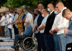Worshippers wearing masks to help stop the spread of the coronavirus, offer Eid al-Adha prayer in front of the Gazi Husrev-beg mosque in Sarajevo, Bosnia, Friday, July 31, 2020.
