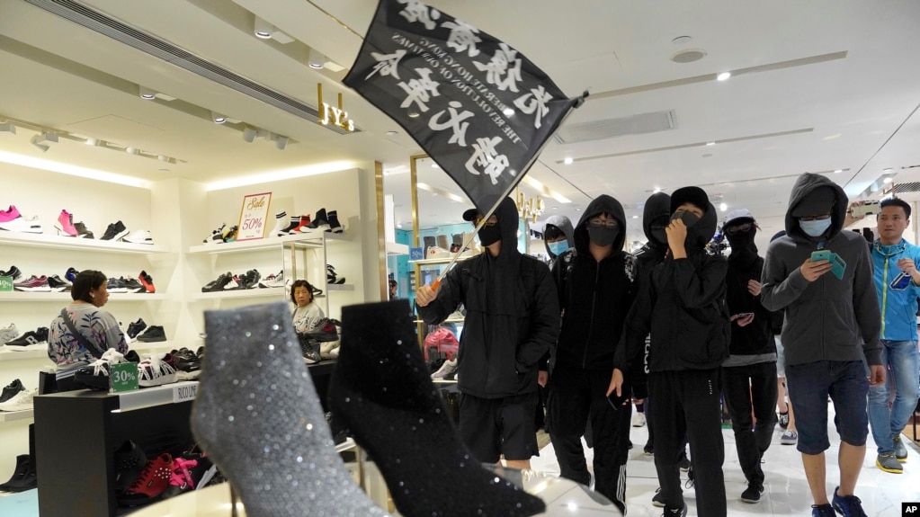 Manifestantes en Hong Kong pasean una bandera que dice "Liberar a Hong Kong, la revolución de nuestros tiempos" durante una marcha por un centro comercial el 26 de diciembre de 2019.