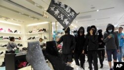 Manifestantes en Hong Kong pasean una bandera que dice "Liberar a Hong Kong, la revolución de nuestros tiempos" durante una marcha por un centro comercial el 26 de diciembre de 2019.