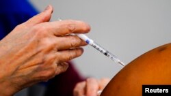 FILE - A health worker administers COVID-19 vaccine at the Keystone First Wellness Center in Chester, Pa., Dec. 15, 2021. On Dec. 17, a federal appellate panel allowed President Joe Biden's COVID-19 vaccine mandate for larger private employers to move ahead.