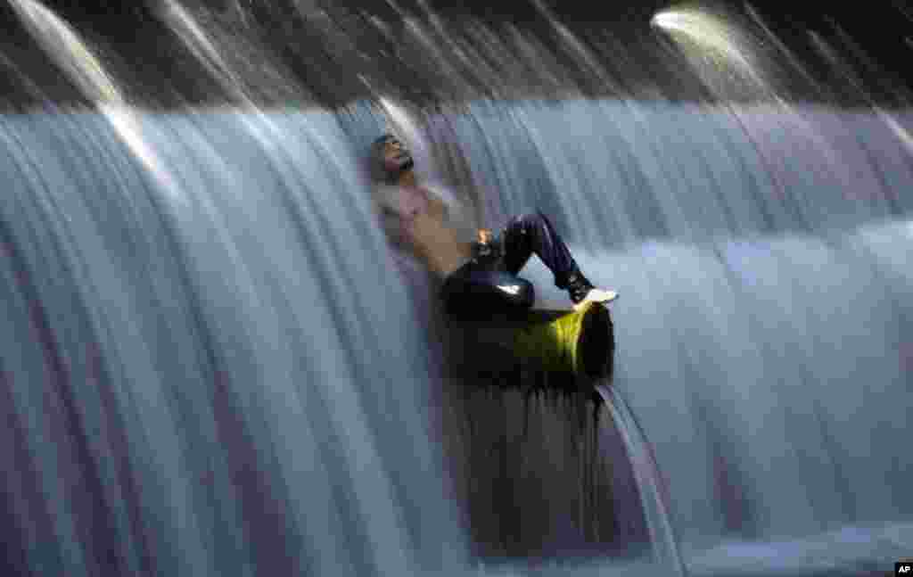 A man cools off in a stream during hot weather in Islamabad, Pakistan.