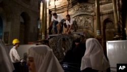 FILE - Christian nuns watch as experts begin renovation of Jesus' tomb in the Church of the Holy Sepulchre in Jerusalem's old city, June 6, 2016. The team has begun a historic renovation at the spot where Christians believe Jesus was buried, overcoming longstanding religious rivalries to carry out the first repairs in more than 200 years.