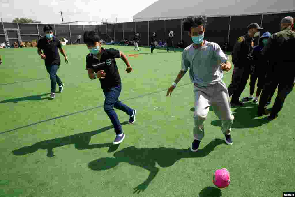 Ni&#241;os migrantes juegan f&#250;tbol en un peque&#241;o terreno dentro del centro de detenci&#243;n.