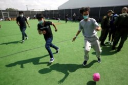 Niños migrantes juegan fútbol en un pequeño campo en el Centro de Detención del Departamento de Seguridad Nacional en Donna, Texas, el principal lugar de detención de niños no acompañados.