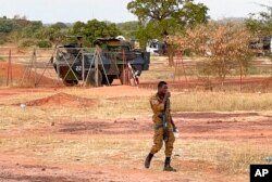 FILE - A Burkinabe soldier walks past a French Armoured Personnel Carrier, part of a French military convoy, heading to Niger, stopped by protesters in Kaya, Burkina Faso, Nov. 20, 2021.