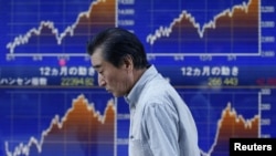 A man walks past a stock quotation board outside a brokerage in Tokyo, June 3, 2013.