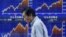 A man walks past a stock quotation board outside a brokerage in Tokyo, June 3, 2013.