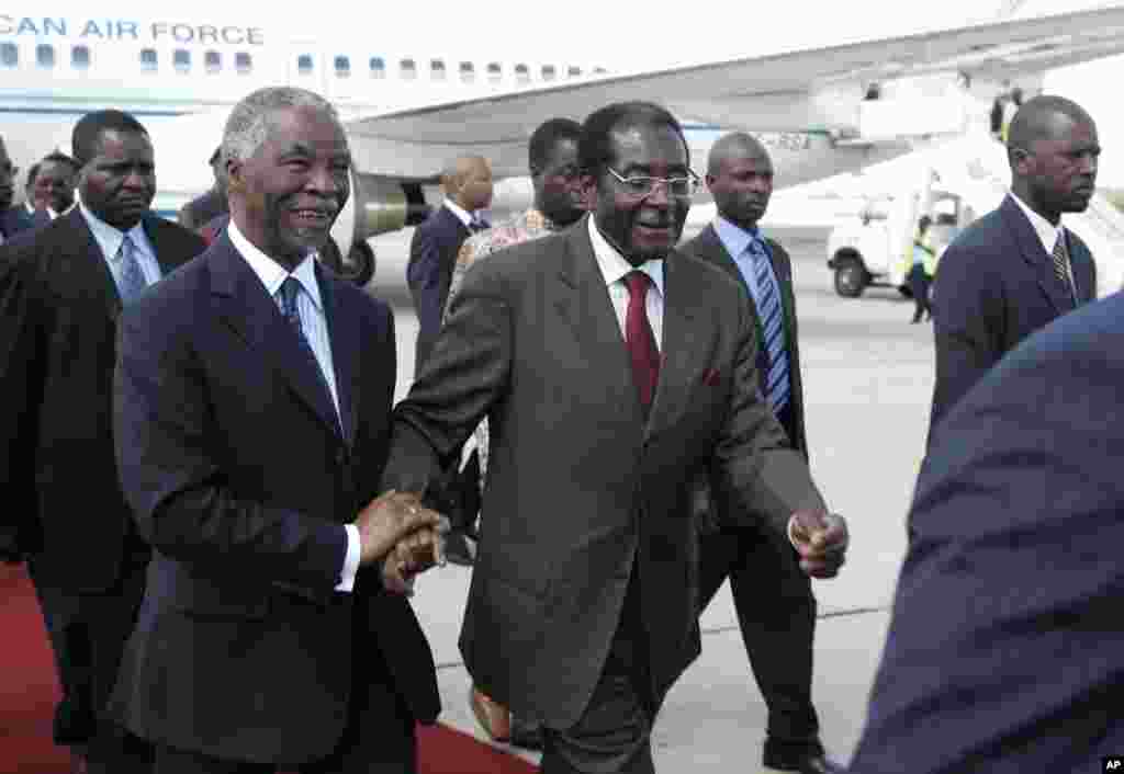 President Robert Mugabe, centre right, welcomes South African President Thabo Mbeki, centre left, of South Africa at Harare International Airport, Saturday, April, 12, 2008. Mbeki was in Zimbabwe enroute to Zambia for a conference aimed at pushing the Zimbabwean government to release the results of the 2008 Presidential election.