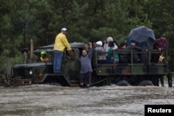 A man wearing a Houston Texans shirt, the local professional American football team, raises his arm as residents are rescued by a truck from floods caused by Tropical Storm Harvey in east Houston, Texas, U.S. August 29, 2017.