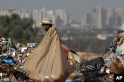 In this May 12, 2014 photo, Divan Rosa carries a bag loaded with recyclable trash as he works inside the Estrutual landfill in Brasilia, Brazil.