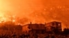 FILE - A wildfire approaches houses in the village of And Loutro, south of Athens, Greece, Sept. 30, 2024. 