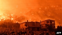 FILE - A wildfire approaches houses in the village of And Loutro, south of Athens, Greece, Sept. 30, 2024. 