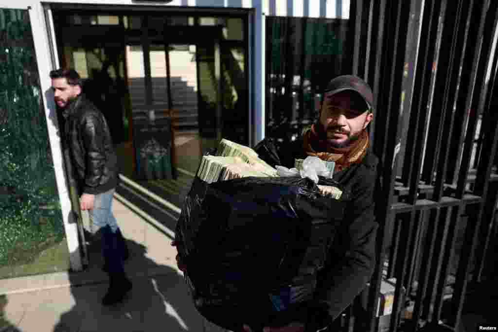 A workers carries a bag of Syrian currency notes to Syrian central bank in Damascus, after the ousting of President Bashar al-Assad, in Damascus.