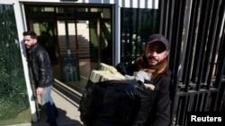 A workers carries a bag of Syrian currency notes to Syrian central bank, after the ousting of Syria's Bashar al-Assad, in Damascus, Dec. 16, 2024. 