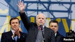 U.S. Senator John McCain (C) waves to pro-European intergration protesters during a mass rally at Independence Square in Kyiv December 15, 2013. Flanking hi, are U.S. Senator Chris Murphy (L) and one of Ukraine's opposition leaders, Oleh Tyahnybok.
